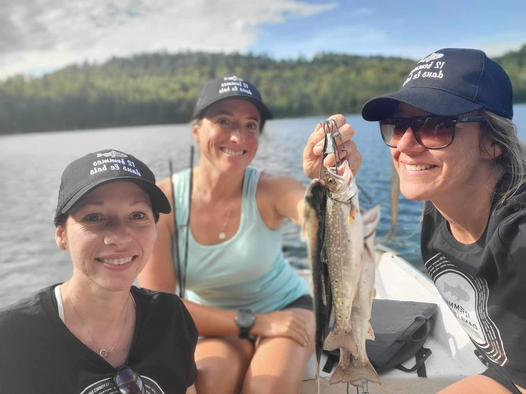 Trois femmes dans un bateau tenant un poisson après une sortie de pêche